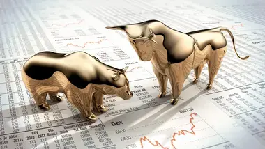 Gold bull and gold bear facing off on newspaper
