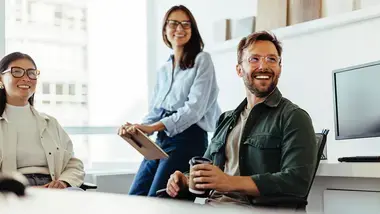 Young group of smiling people sitting at a conference table.